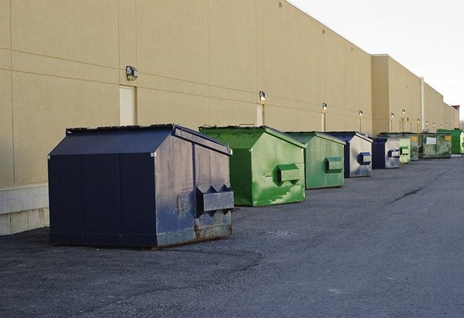 construction workers toss wood scraps into a dumpster in Buena